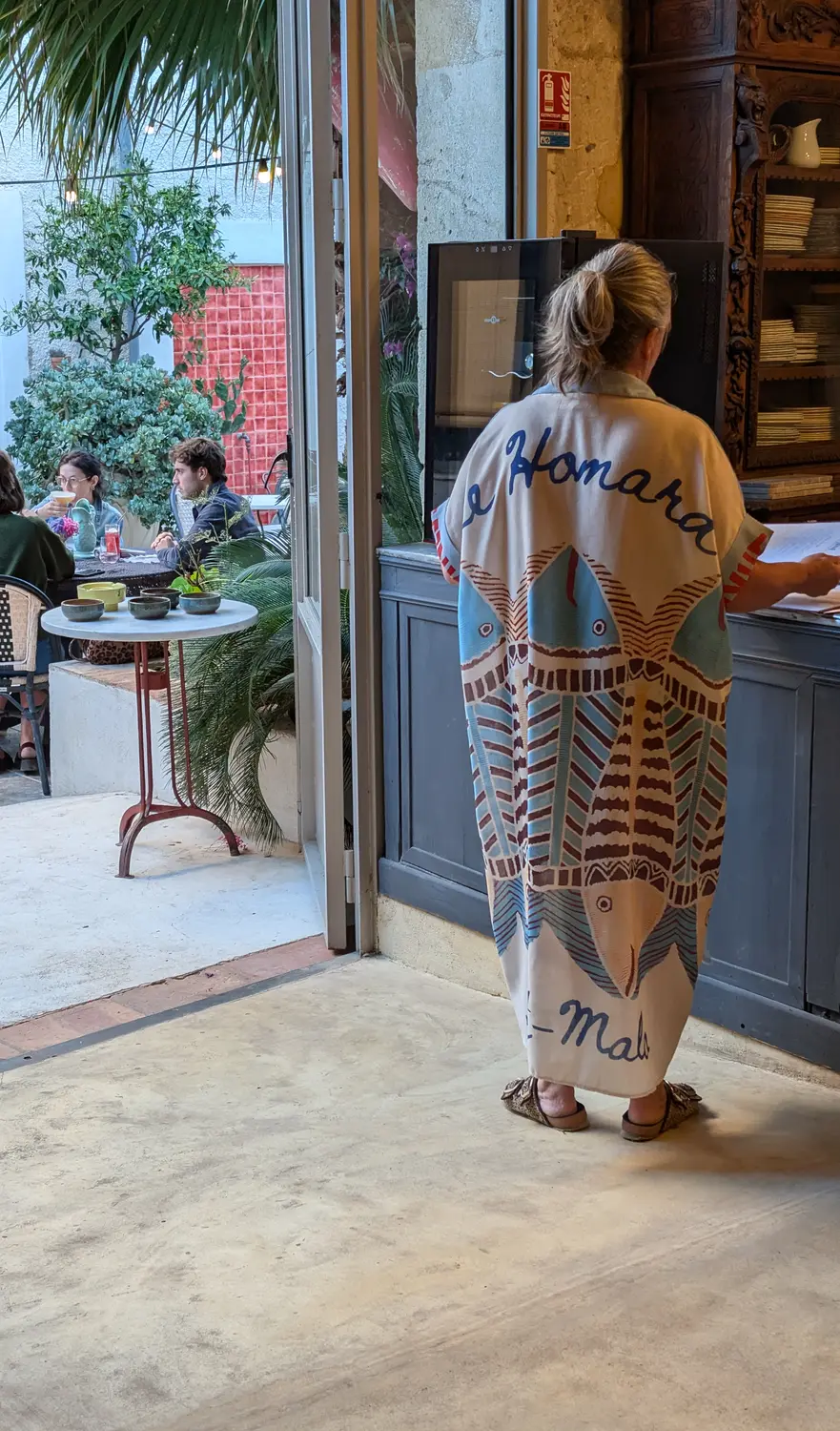 La patronne sur le seuil, la cour occupée derrière elle